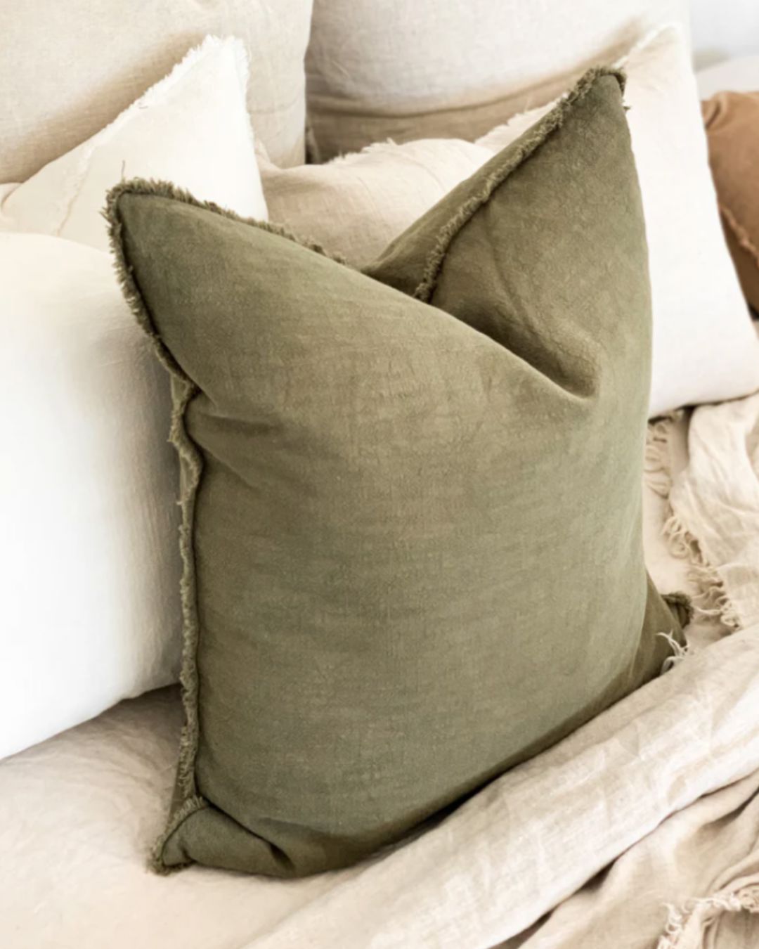 Green pillow with frayed edges on a beige sofa