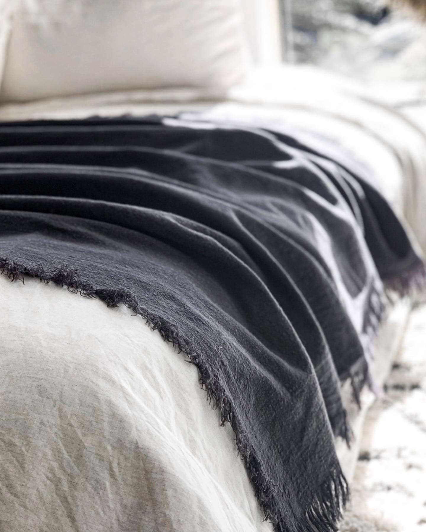 Gray blanket draped over a white surface with a blurred background