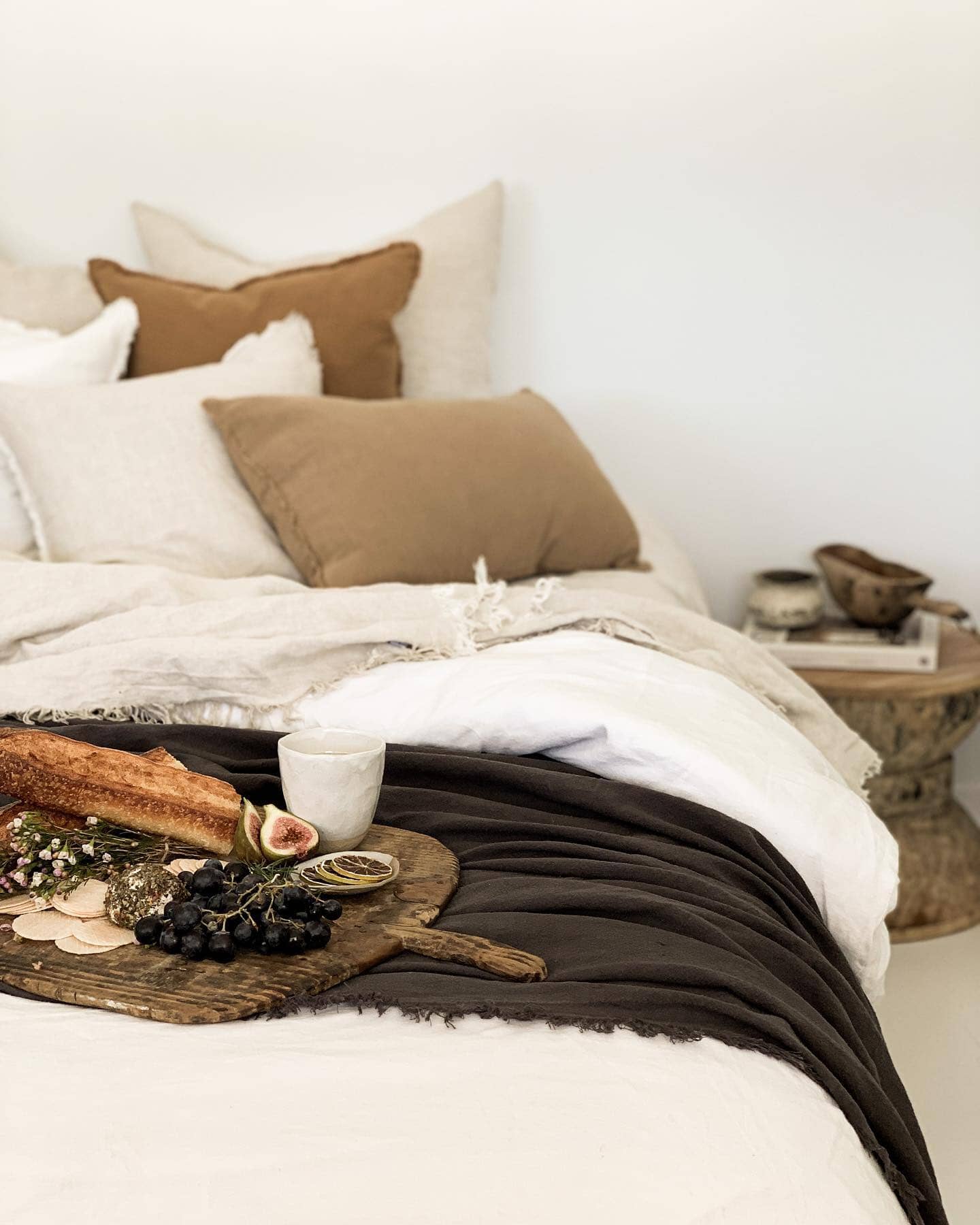 Cozy bedroom with a bed featuring brown and white pillows, a wooden side table with decor items.
