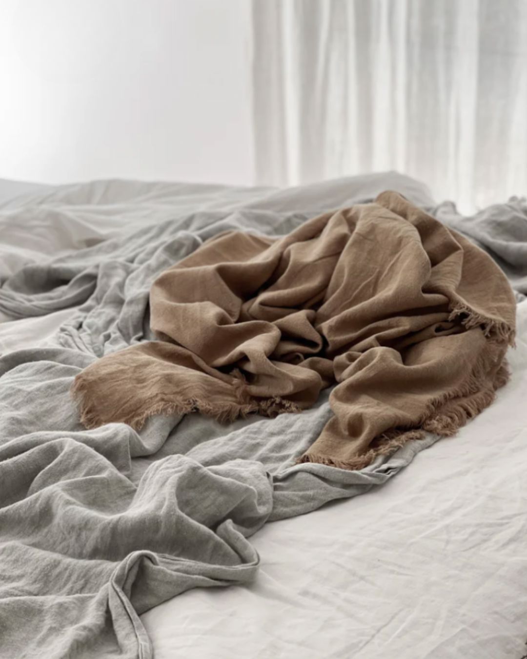 Brown blanket draped over a bed with gray bedding