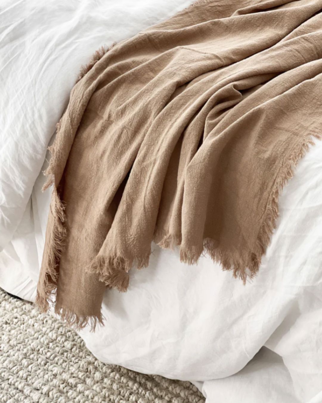 Brown blanket draped over a white bed