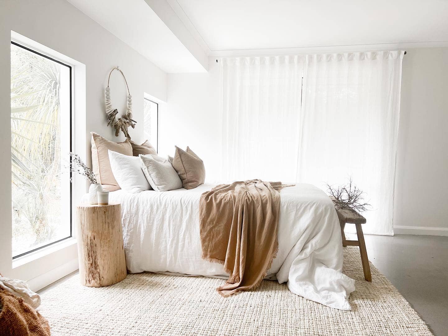 Neatly made bed with white bedding and brown throw blanket in a bright bedroom.
