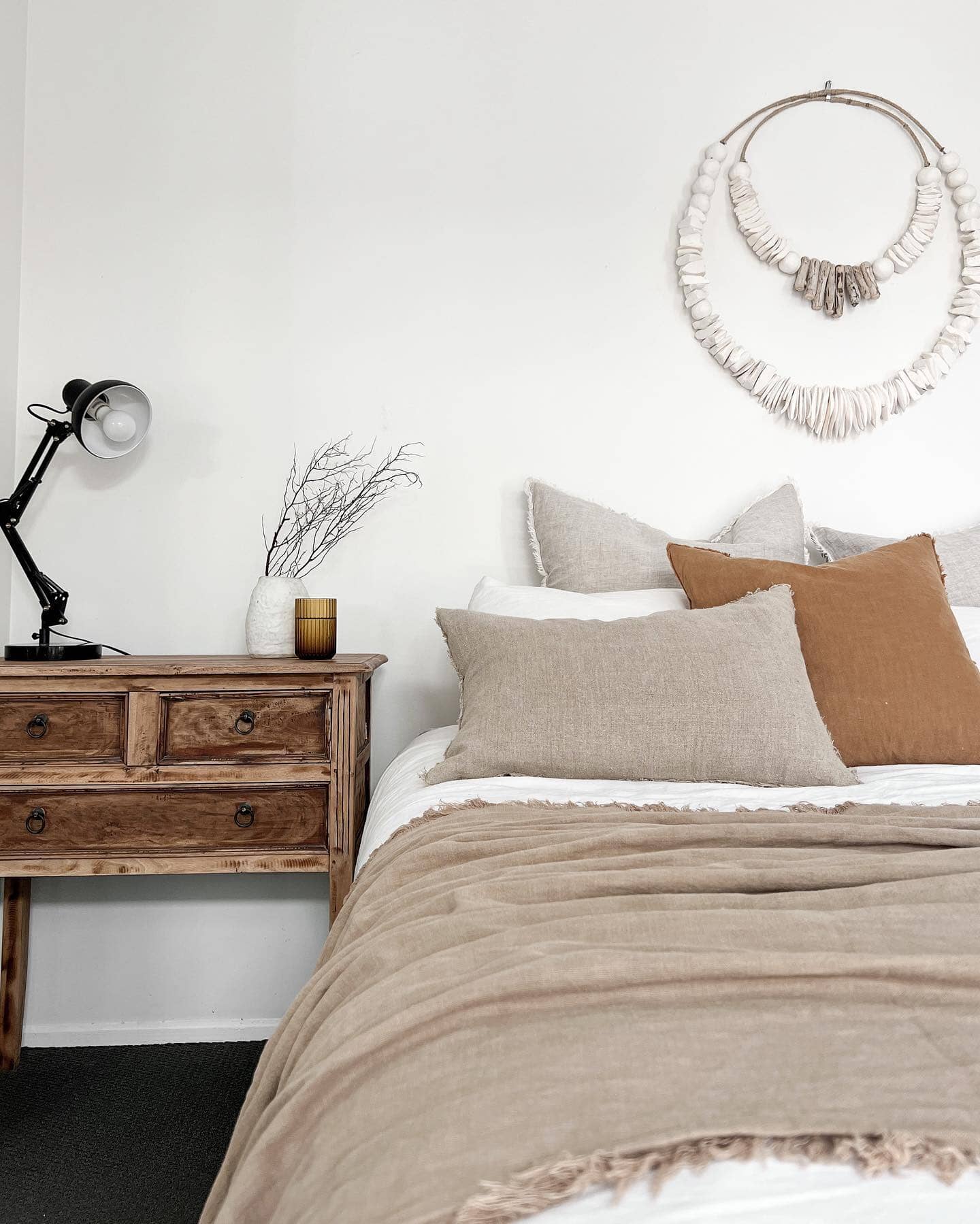 Neatly made bed with pillows and a wooden nightstand in a bedroom setting.