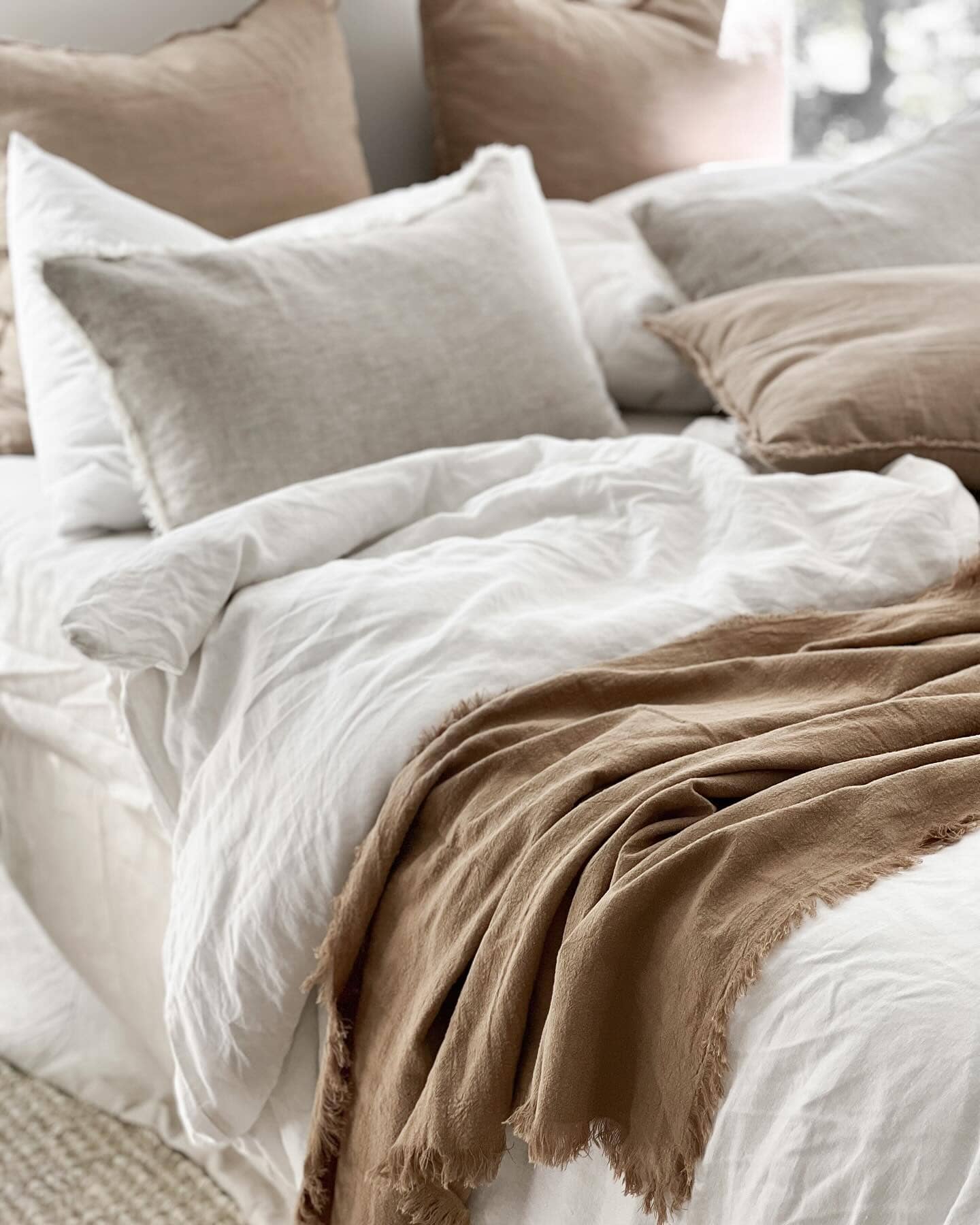 Neatly made bed with beige and white bedding