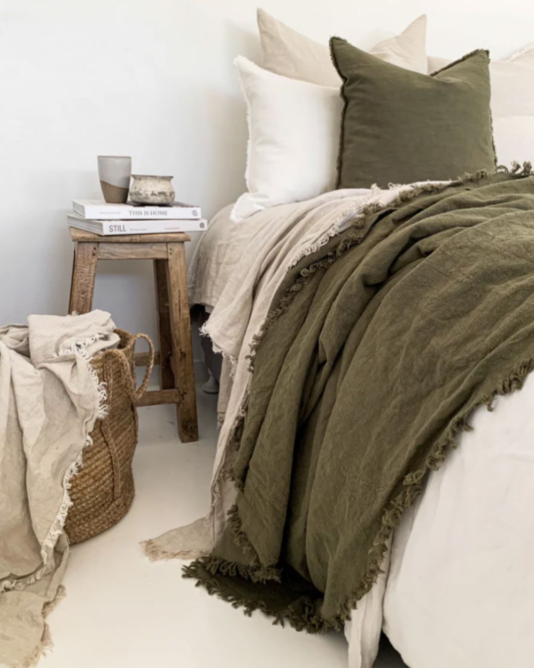 Bed with olive green bedding and white pillows in a cozy bedroom setting.