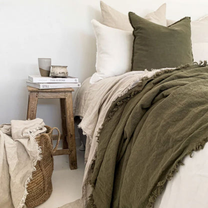 Bed with olive green bedding and white pillows in a cozy bedroom setting.