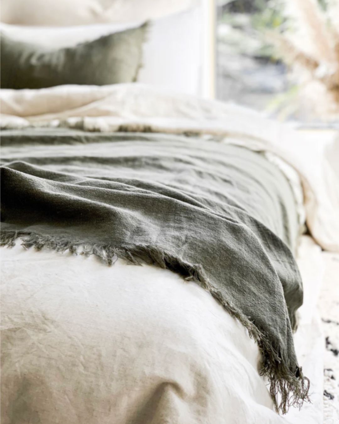 Gray blanket draped over a white surface with a blurred natural background