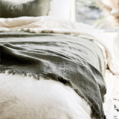 Olive blanket draped over a white surface with a blurred natural background