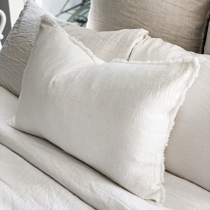 Close-up of textured pillows on a bed with neutral tones.