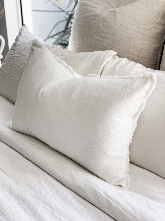 Close-up of textured pillows on a bed with neutral tones.