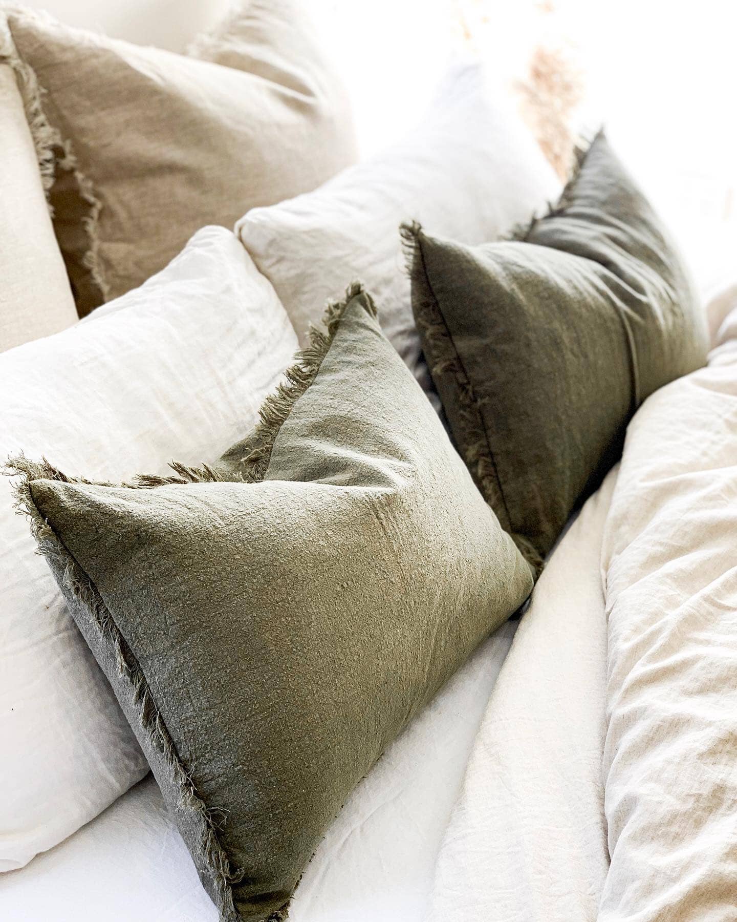 Close-up of textured pillows on a bed with neutral tones.