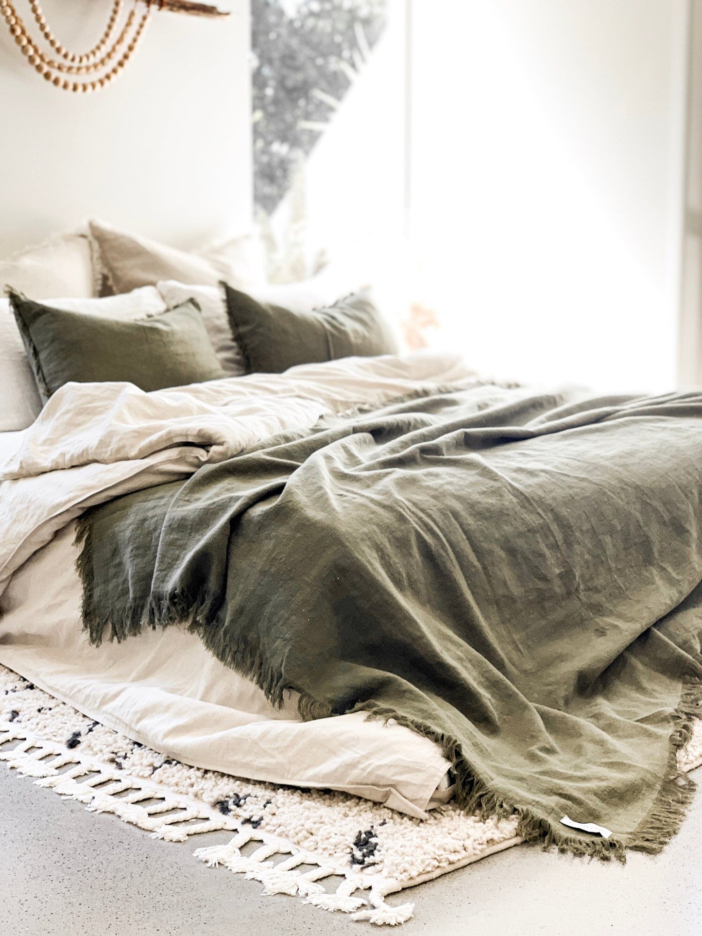 Neatly made bed with green and beige bedding in a softly lit room.