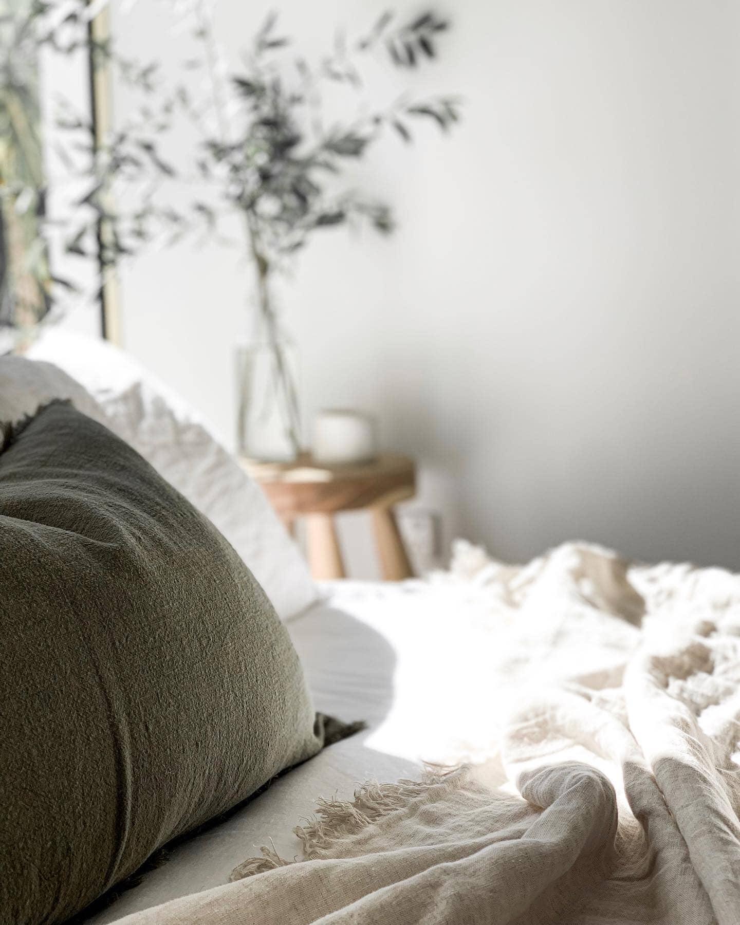 Cozy bedroom with a bed featuring a green pillow and white blanket, blurred background
