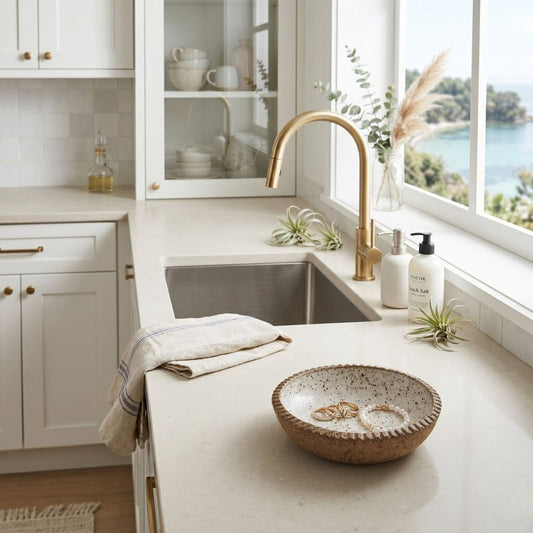 Modern kitchen with white cabinets, gold faucet, and a bowl on the counter.