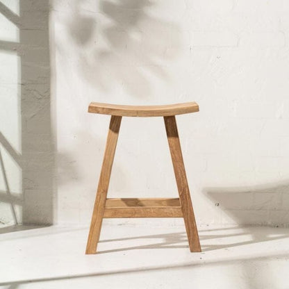 Wooden stool against a white wall with sunlight casting shadows.