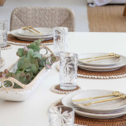 Elegant table setting with plates, glasses, and decorative elements on a white table.