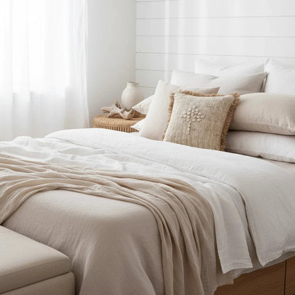 Neatly made bed with beige and white bedding in a bright bedroom.