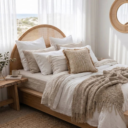Neatly made bed with beige and white bedding in a bright bedroom.