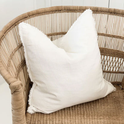 White pillow on a wicker chair with a white wall background