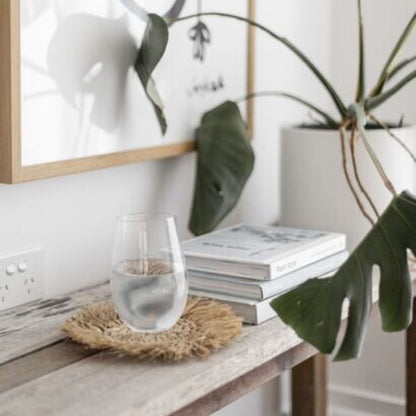 Table with a glass of water, books, and a plant in a minimalistic room.