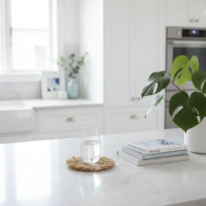 Modern kitchen with a white countertop, glass of water, books, and a plant.