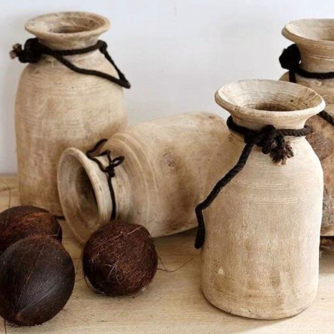 Set of rustic clay jars with coconuts on a wooden surface