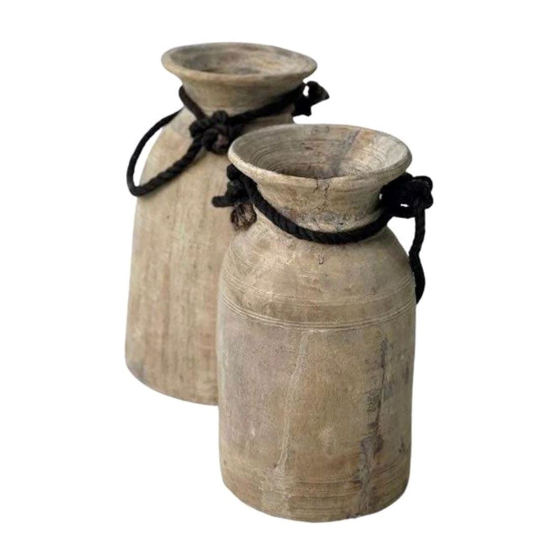Two rustic wooden jars with black rope handles on a white background