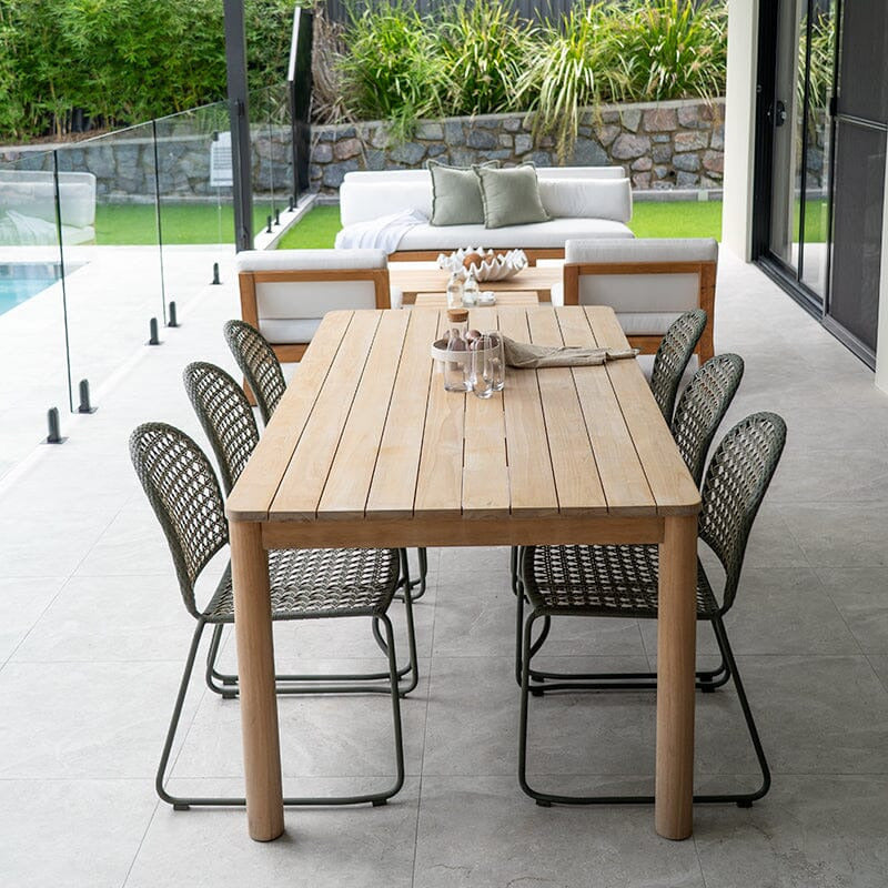Outdoor patio with wooden dining table and chairs near a pool