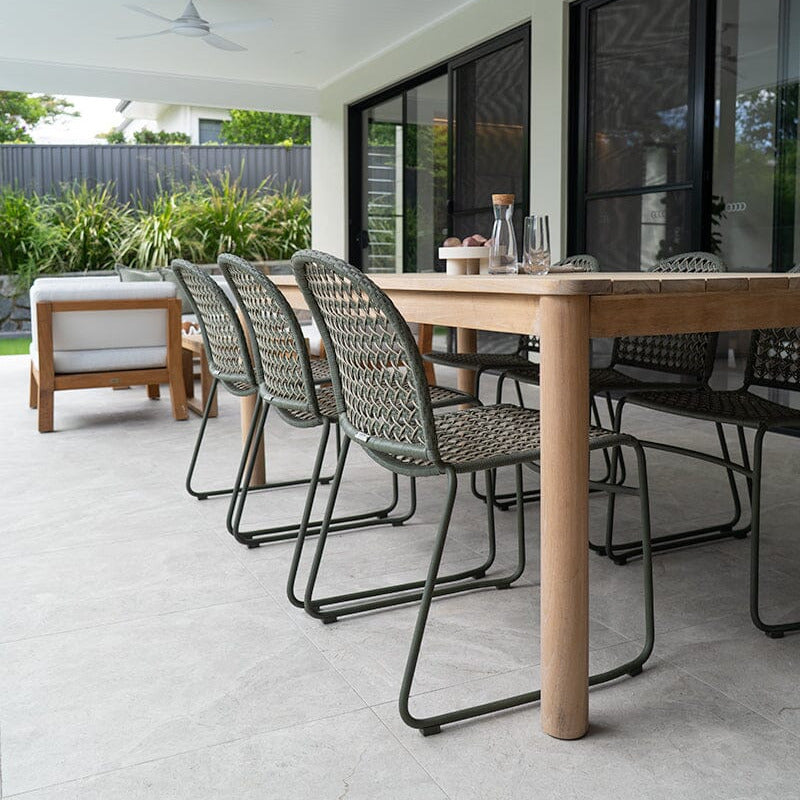 Outdoor patio with wooden table and chairs on a concrete floor.