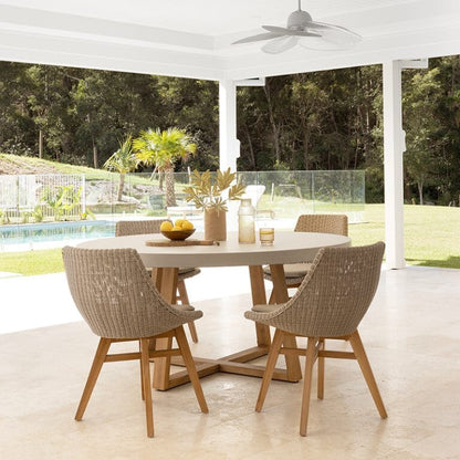 Outdoor dining area with a round table and chairs near a pool and garden.