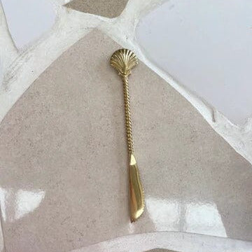 Gold spoon with decorative handle on a textured surface