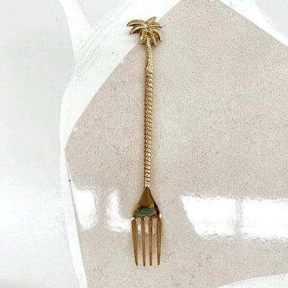 Gold fork with palm tree design on a white background