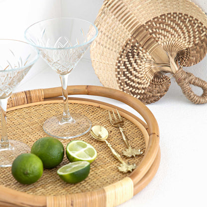 Rattan tray with limes, glasses, and a fan on a white background